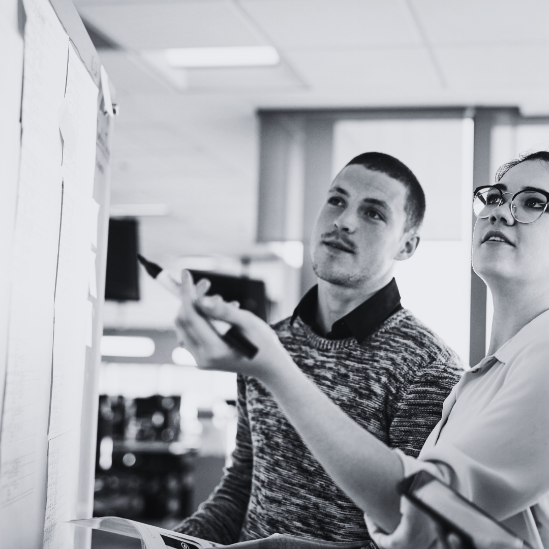 Two people looking at a computer screen in an office setting