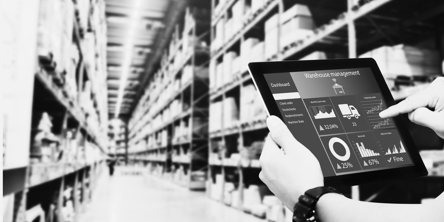 Person holding a tablet with warehouse management software in a warehouse setting